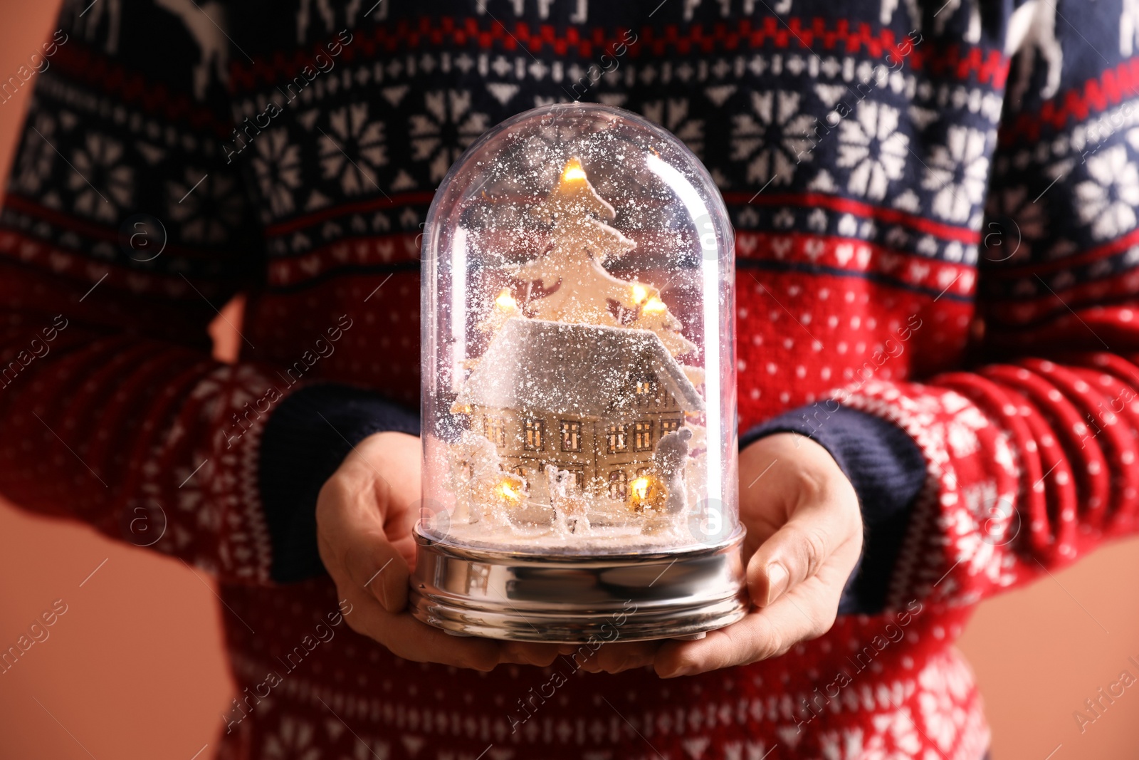 Photo of Man holding decorative snow globe on coral background, closeup