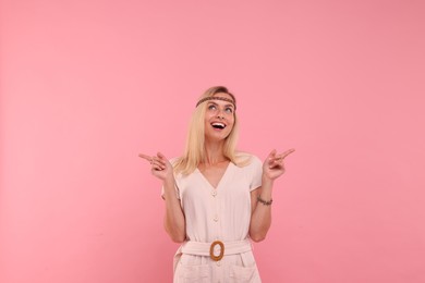 Photo of Portrait of happy hippie woman pointing at something on pink background