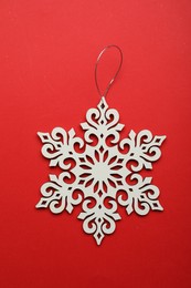 Photo of Beautiful decorative snowflake on red background, top view
