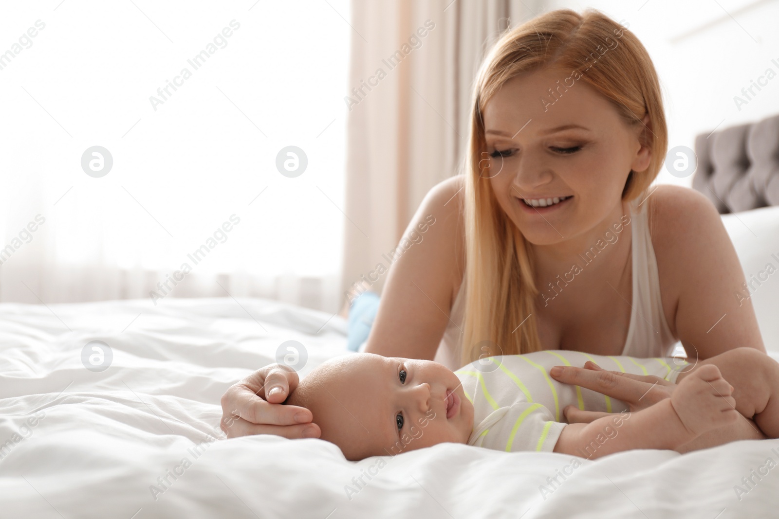 Photo of Mother with her little baby on bed at home