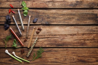 Photo of Flat lay composition with various spices, test tubes and fresh herbs on wooden background. Space for text