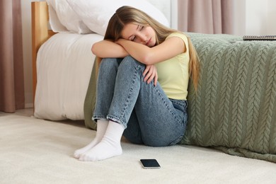 Photo of Upset teenage girl sitting alone in room at home