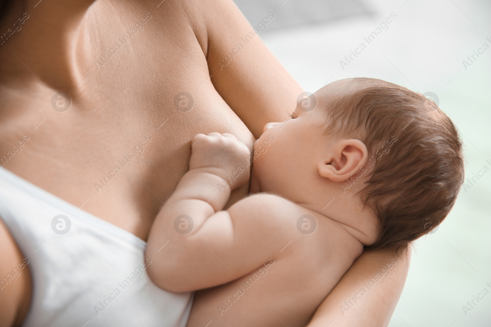 Photo of Young woman breastfeeding her baby on blurred background, closeup