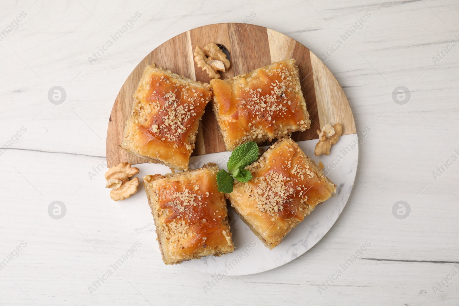 Photo of Eastern sweets. Pieces of tasty baklava on white wooden table, top view