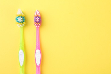 Photo of Colorful plastic toothbrushes on yellow background, flat lay. Space for text