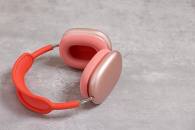 Photo of Stylish pink headphones on light grey table, closeup. Space for text