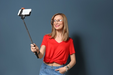 Photo of Attractive young woman taking selfie on color background