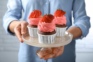 Woman holding dessert stand with sweet cupcakes, closeup