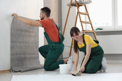 Workers hanging stylish gray wallpaper in room