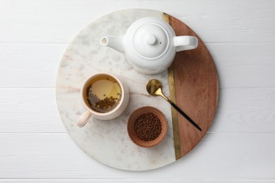 Photo of Freshly made buckwheat tea served on white wooden table, top view