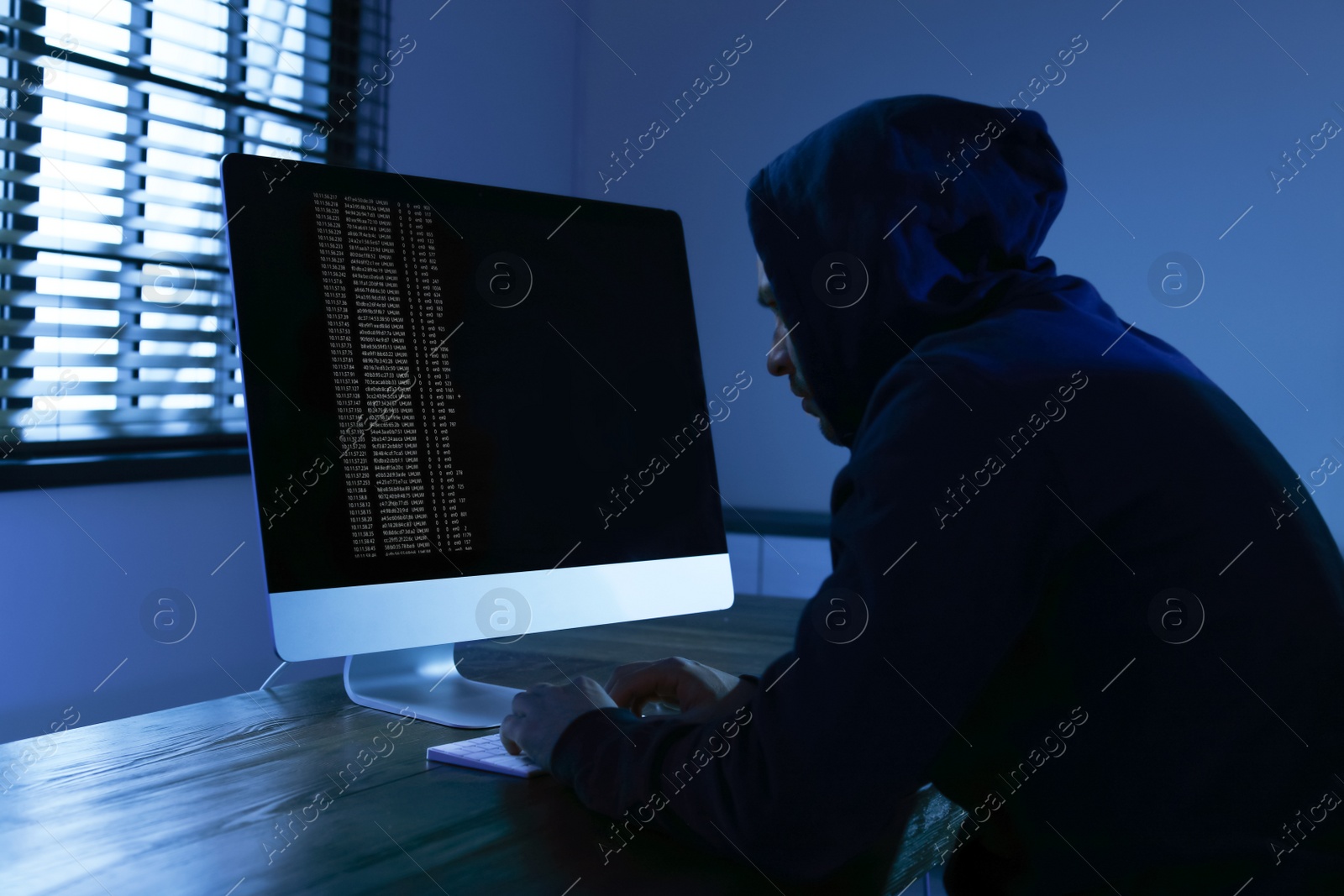 Photo of Man using computer in dark room. Criminal offence