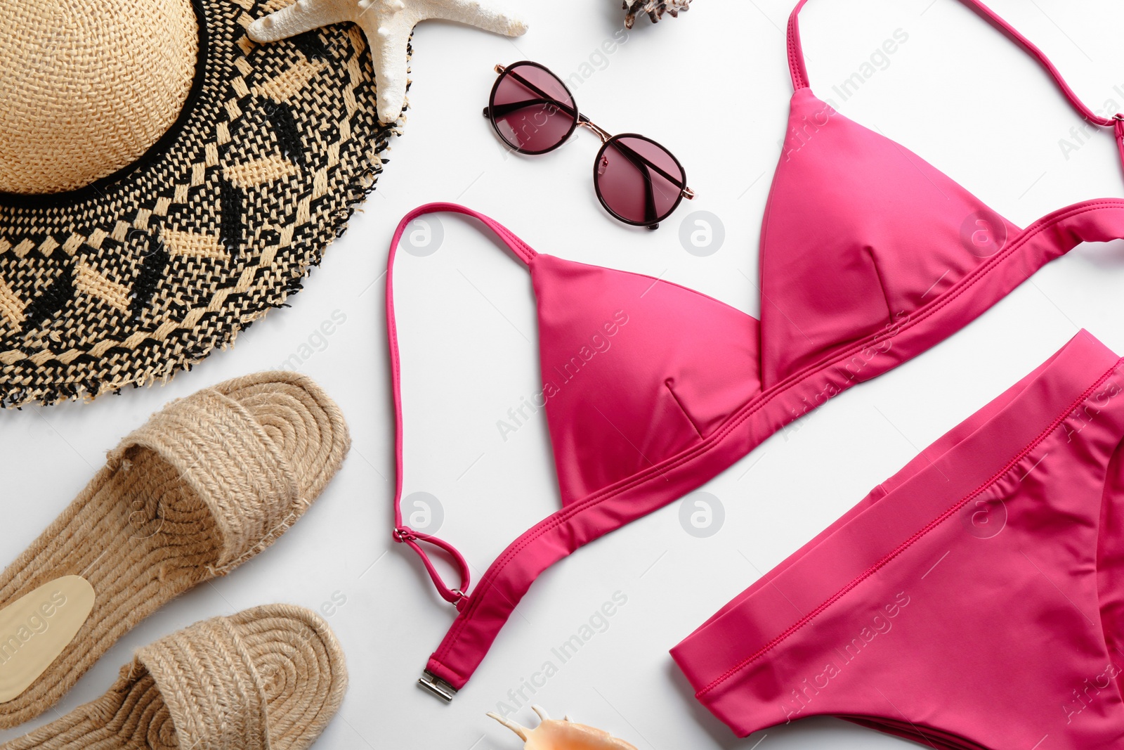 Photo of Beautiful pink bikini and beach accessories on white background, flat lay