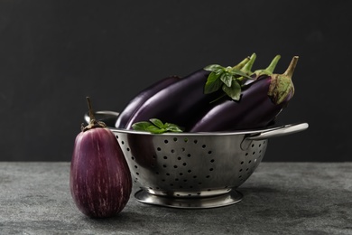 Photo of Ripe purple eggplants and basil on grey table