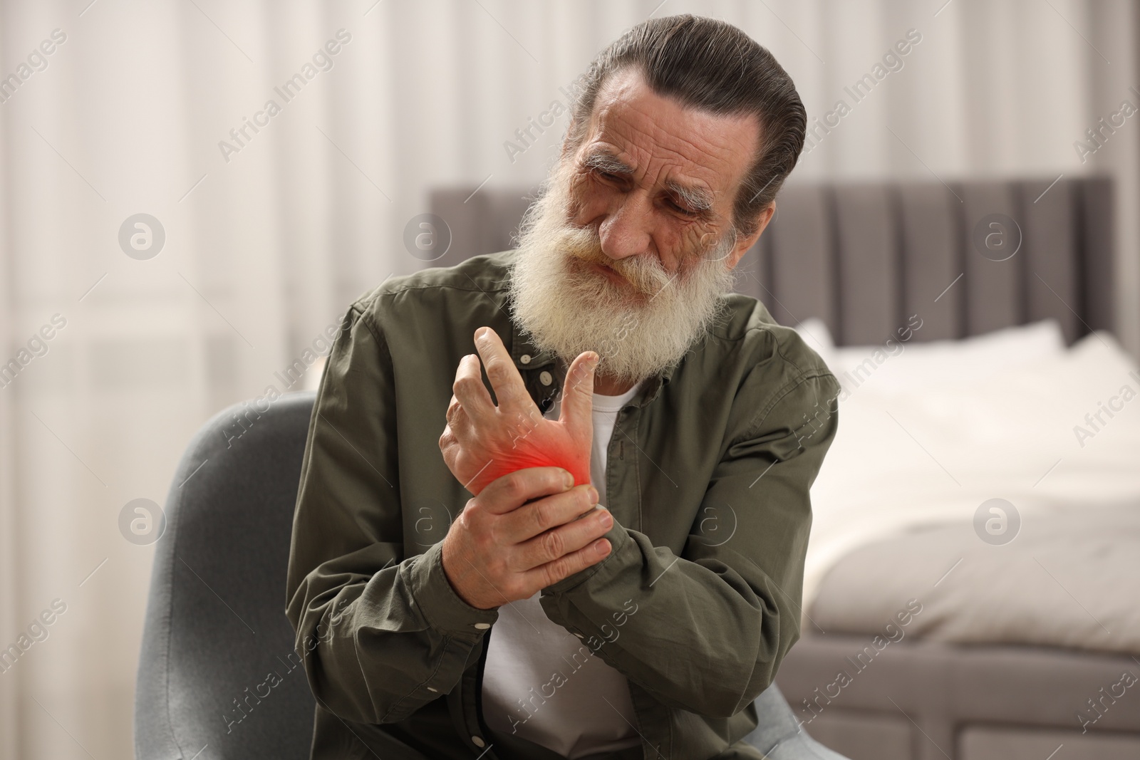 Image of Senior man suffering from pain in wrist indoors