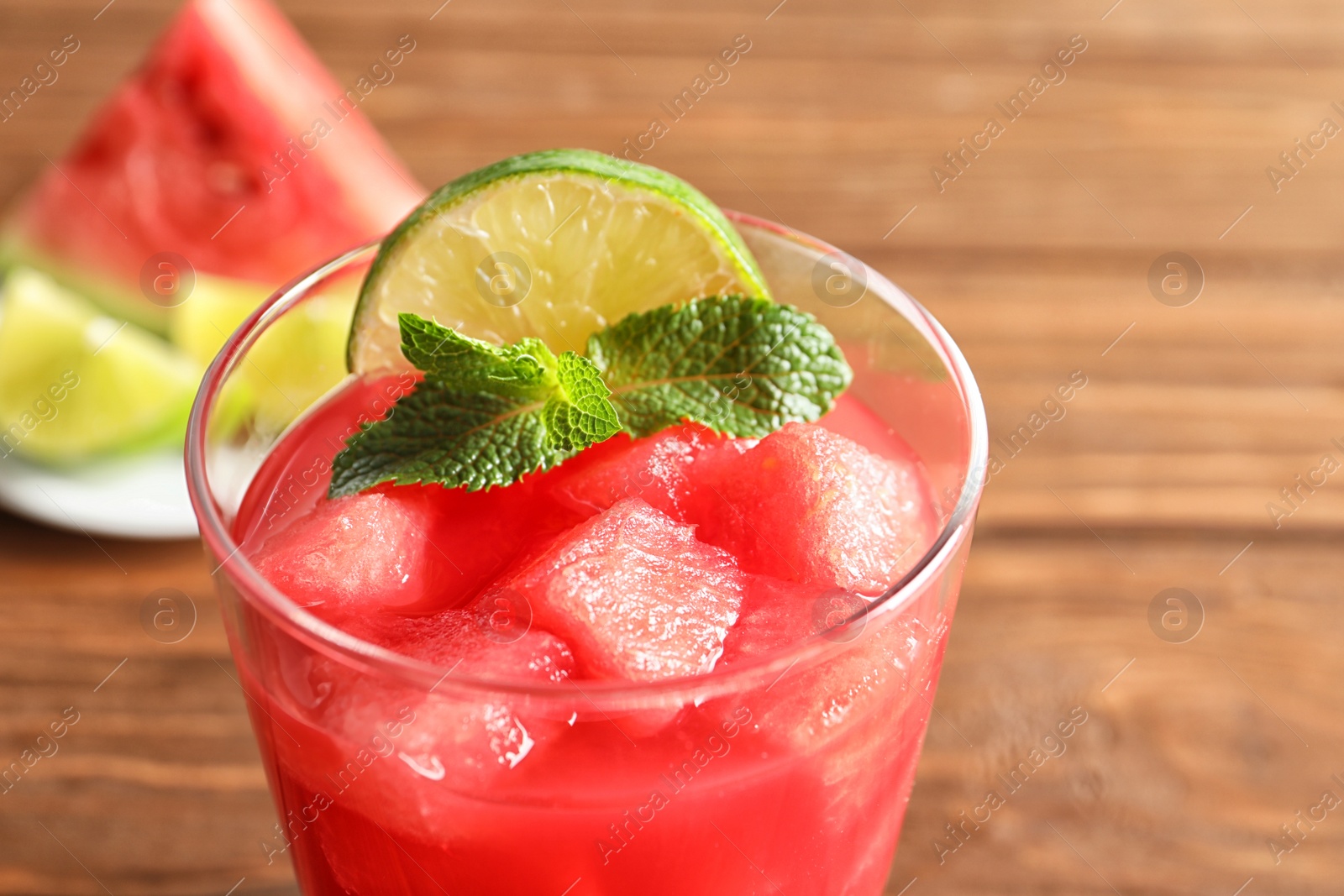 Photo of Tasty summer watermelon drink with lime and mint in glass on table, closeup