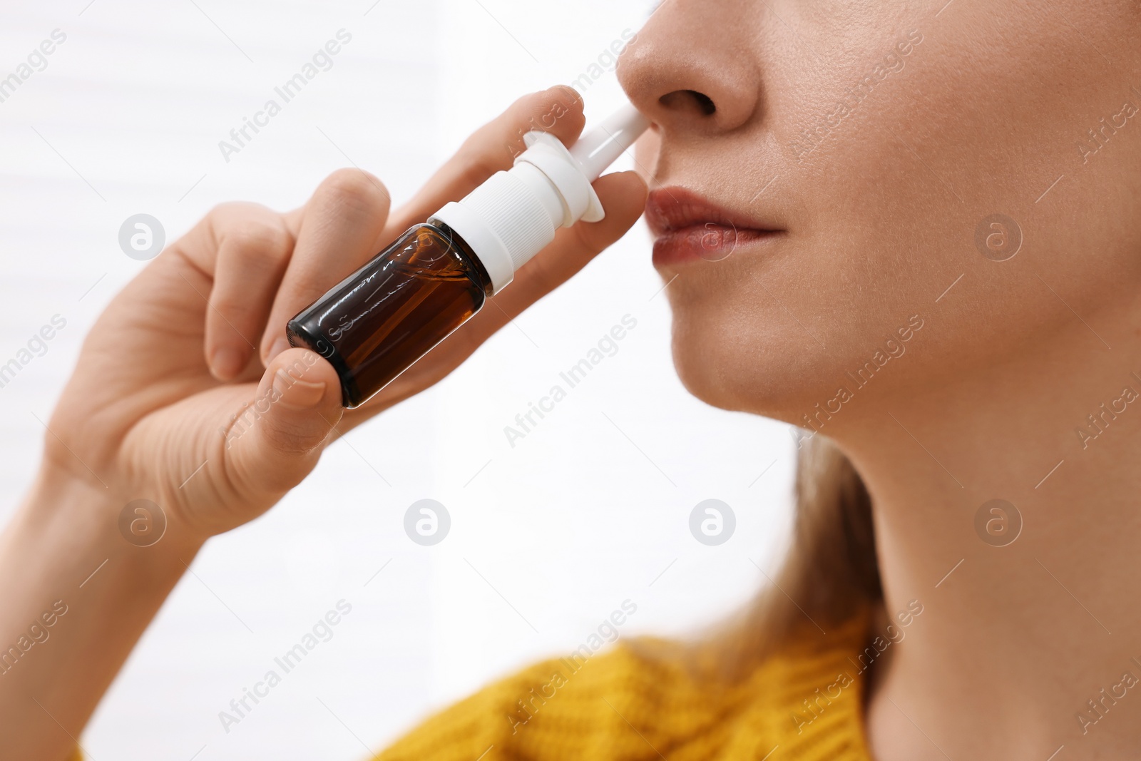 Photo of Medical drops. Young woman using nasal spray indoors, closeup