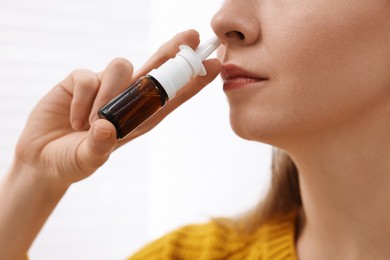 Medical drops. Young woman using nasal spray indoors, closeup