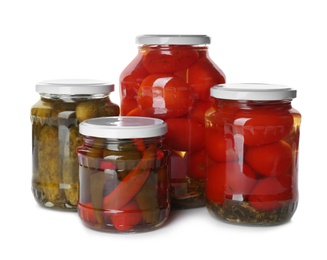 Glass jars with different pickled vegetables on white background