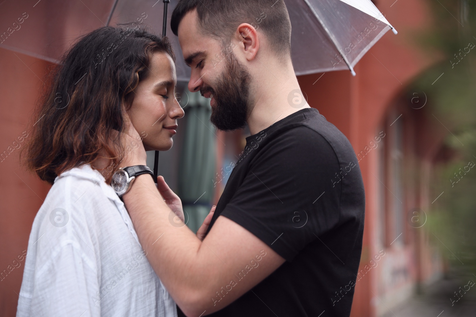 Photo of Young couple with umbrella enjoying time together under rain on city street