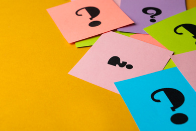 Photo of Paper cards with question marks on yellow background, closeup