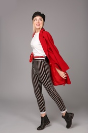 Photo of Young stylish woman in trendy shoes with bum bag on grey background