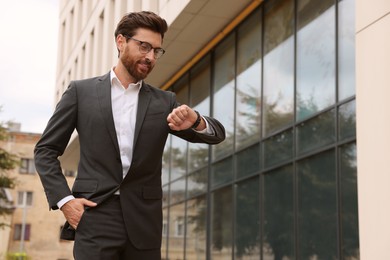 Photo of Handsome bearded businessman in eyeglasses near building outdoors