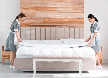 Photo of Young chambermaids making bed in hotel room