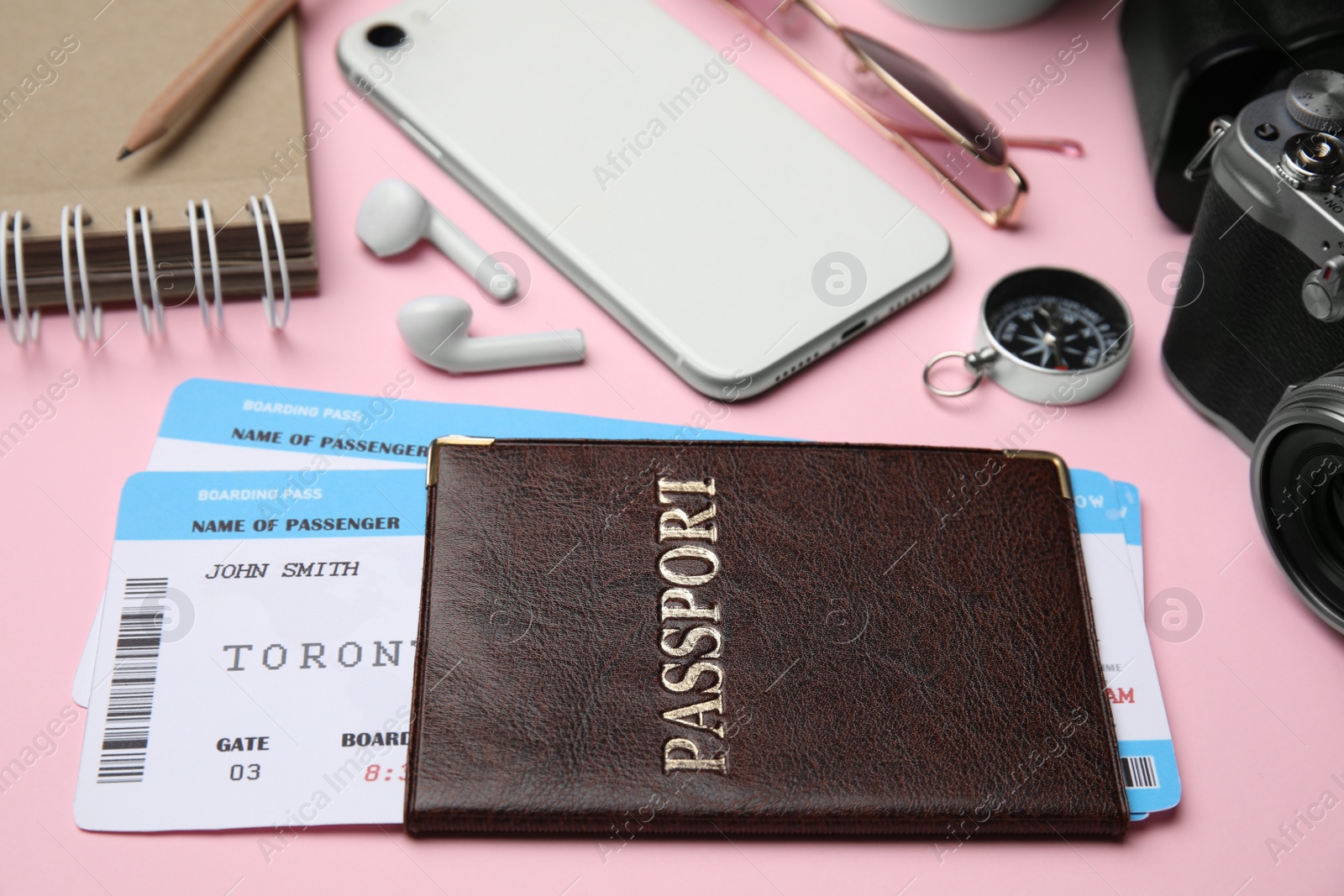 Photo of Passport with tickets among travel items on pink background, closeup