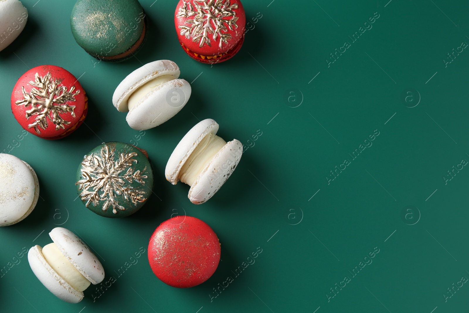 Photo of Beautifully decorated Christmas macarons on green background, flat lay. Space for text