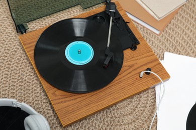 Photo of Stylish turntable with vinyl disc and headphones on carpet at home