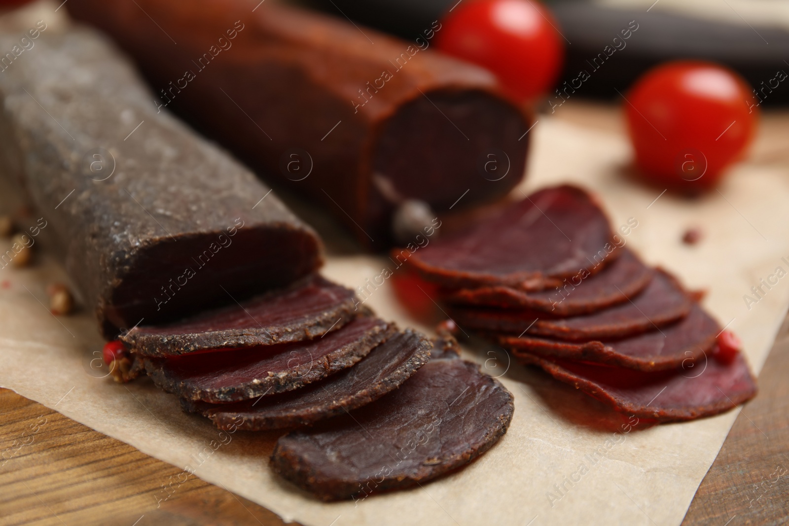 Photo of Delicious dry-cured beef basturma with peppercorns on wooden table, closeup