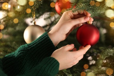 Woman decorating Christmas tree with beautiful red bauble, closeup