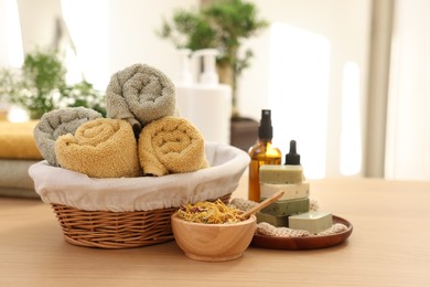 Photo of Dry flowers, soap bars, bottles of essential oils, jar with cream and towels on wooden table indoors, space for text. Spa time