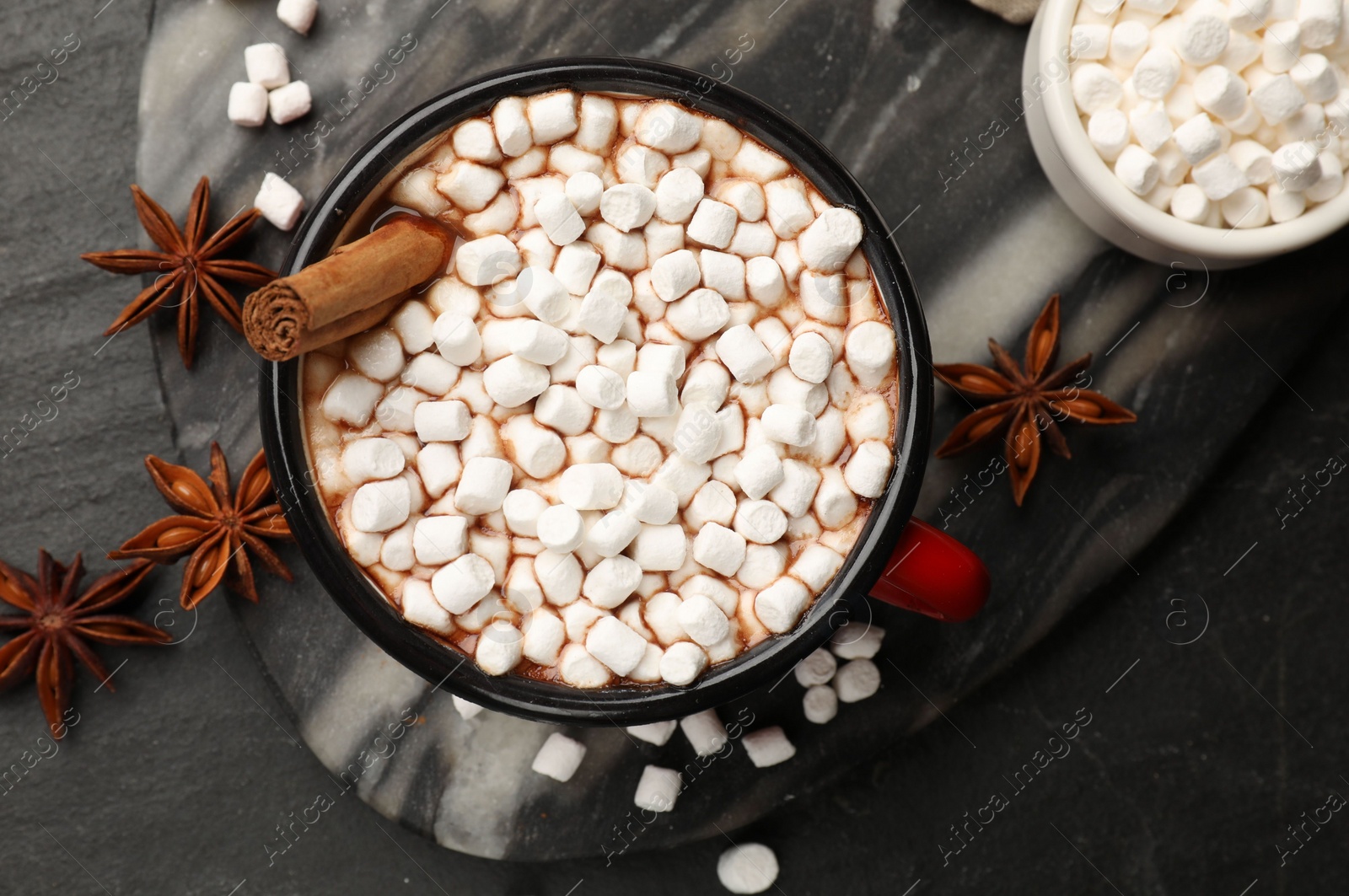 Photo of Tasty hot chocolate with marshmallows on dark textured table, flat lay