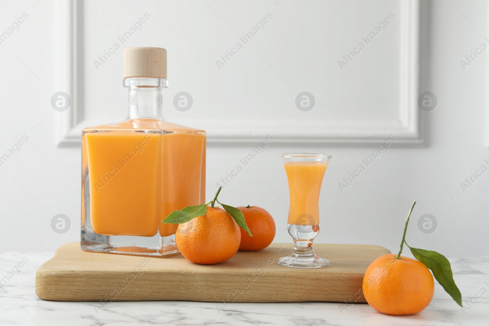 Photo of Delicious tangerine liqueur and fresh fruits on white marble table