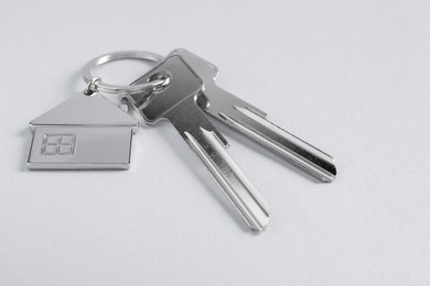 Photo of Keys with keychain in shape of house on light background, closeup