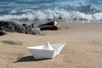 Photo of White paper boat near sea on sunny day, space for text