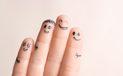 Fingers with drawings of happy faces against light background. Unity concept