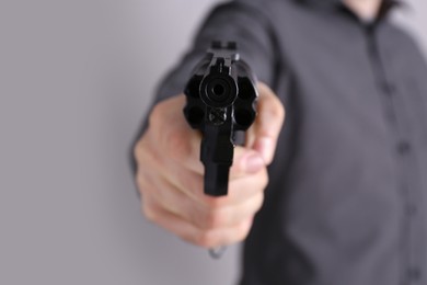 Photo of Man holding gun on grey background, closeup