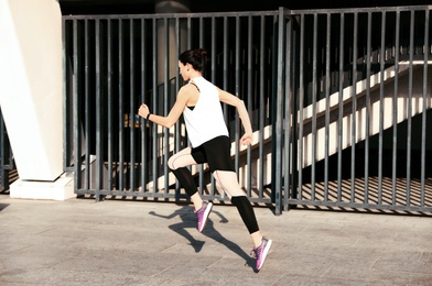 Beautiful sporty young woman running on street