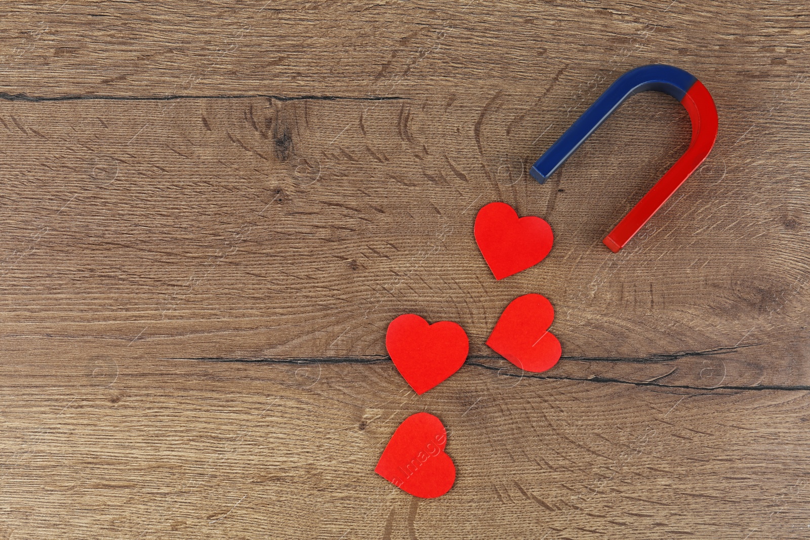 Photo of Magnet and red hearts on wooden table, flat lay. Space for text