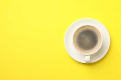 Aromatic coffee in cup on yellow background, top view. Space for text