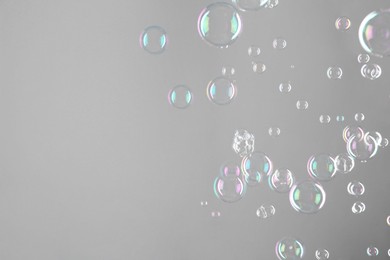 Photo of Beautiful transparent soap bubbles on grey background, space for text