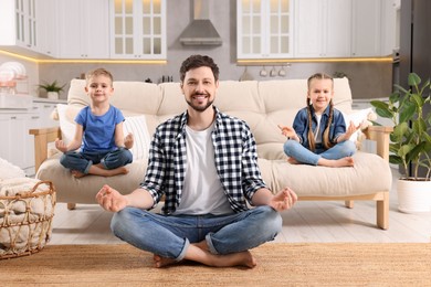 Photo of Father with children meditating together at home. Harmony and zen