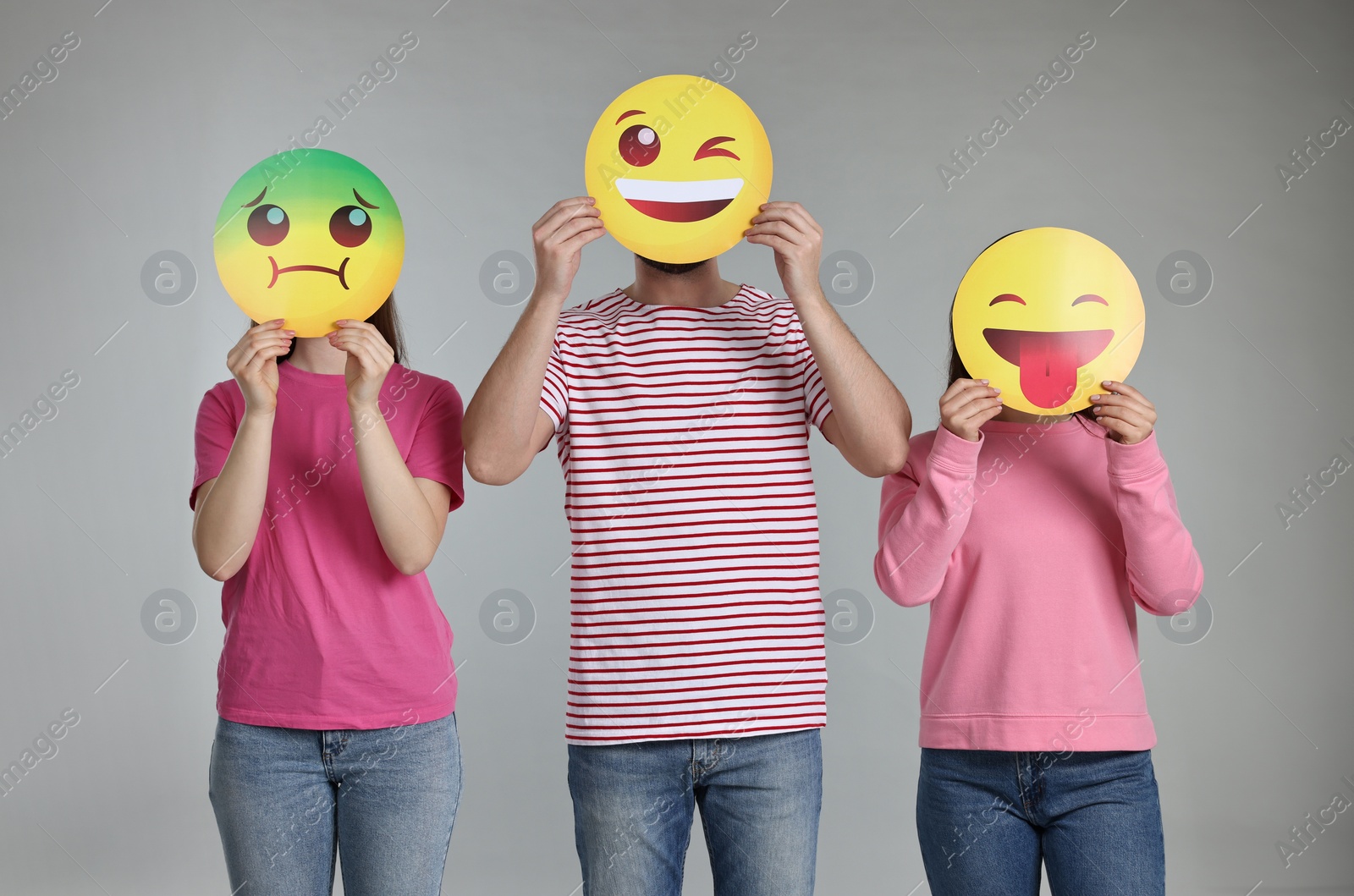 Photo of People covering faces with emoticons on grey background