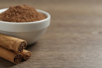 Cinnamon powder and sticks on wooden table, closeup. Space for text