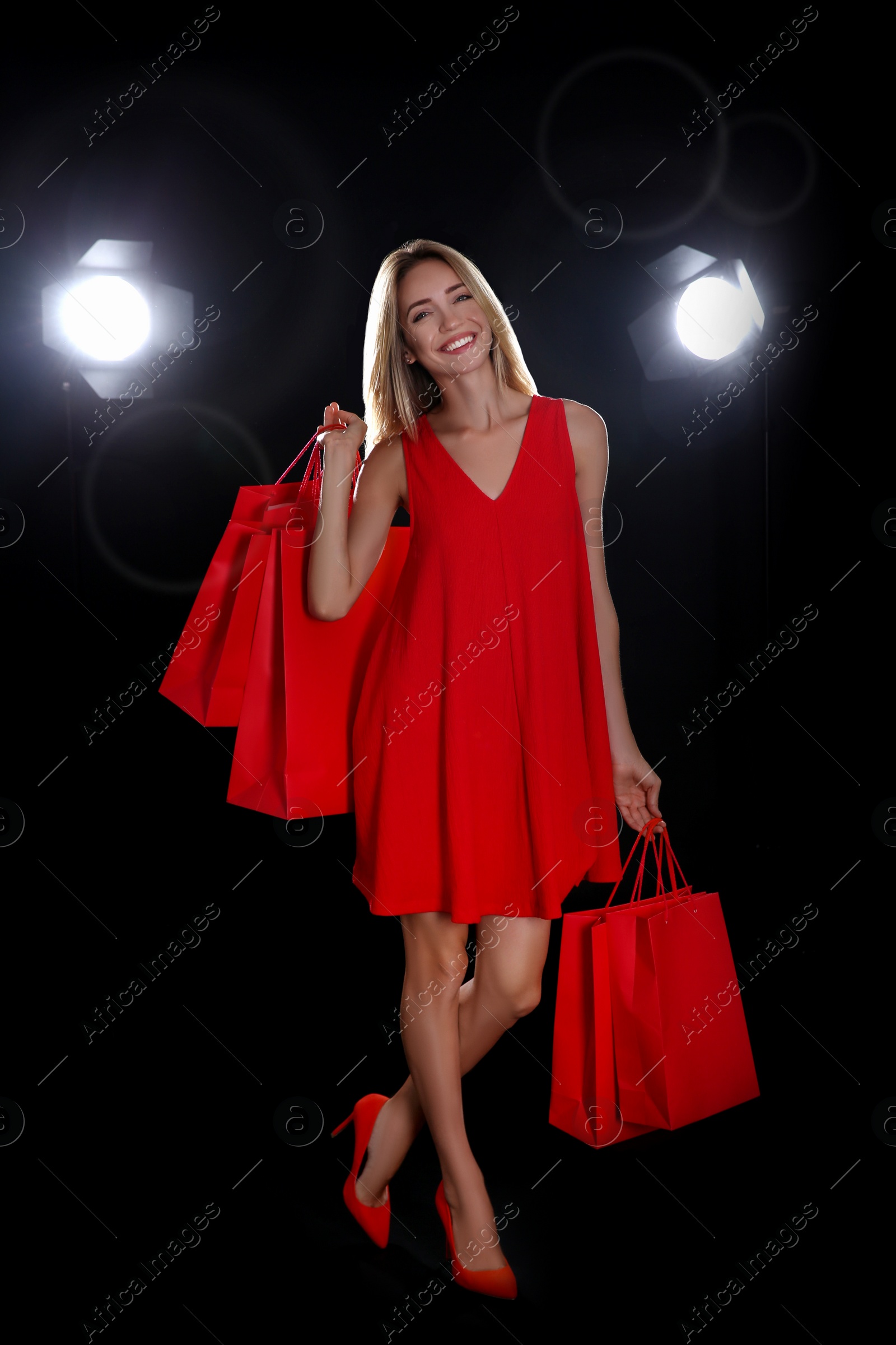 Photo of Happy young woman with shopping bags on dark background. Black Friday Sale