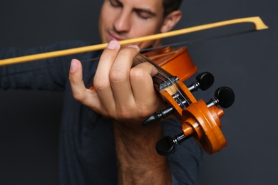 Man playing violin on black background, closeup