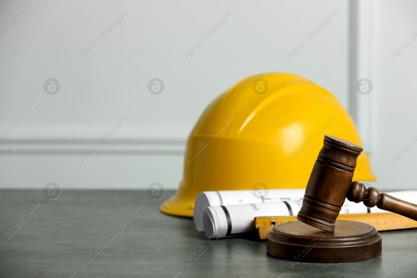 Photo of Construction and land law concepts. Judge gavel, protective helmet with drawings on grey table, space for text