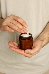 Photo of Man holding jar of hand cream, closeup